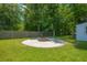 Backyard with a fire pit on a concrete pad, surrounded by lush green grass and mature trees at 439 Temple Rd, Ladson, SC 29456