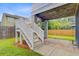 Backyard featuring deck stairs leading to a stone patio and green lawn at 492 Sanders Farm Ln, Wando, SC 29492