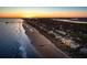 Stunning aerial view of oceanfront homes along a sandy beach at sunset with blue water and clear skies at 505 E Arctic Ave, Folly Beach, SC 29439