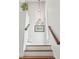 Bright stairway with hardwood stairs, decorative plates, and a framed beach picture on a white wall at 505 E Arctic Ave, Folly Beach, SC 29439