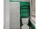 A bathroom with green walls, a white toilet, and a metal shelving unit by the window at 509 E Ashley Ave, Folly Beach, SC 29439