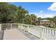 An elevated deck with beige floors, white railings, and a view of surrounding mature trees at 509 E Ashley Ave, Folly Beach, SC 29439