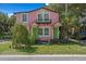 Charming pink two-story home with a small balcony, green doors, and lush landscaping at 509 E Ashley Ave, Folly Beach, SC 29439