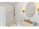 Bright bathroom featuring a walk-in shower, marble counters, brushed gold hardware and a round mirror at 509 W Ashley Ave, Folly Beach, SC 29439
