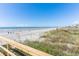 Beach and dunes view with wooden railing, showcasing a sunny day at the ocean at 509 W Ashley Ave, Folly Beach, SC 29439