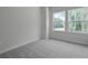 The bedroom has two windows with outdoor views, and neutral walls and carpeting at 560 Scholar Way, Summerville, SC 29486