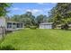Spacious backyard featuring the house, a detached garage, lush green lawn, and mature trees under a bright blue sky at 604 Longstreet St, Summerville, SC 29486