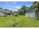 Wide backyard view with the house, screened-in sunroom, detached garage, and lush green lawn and trees at 604 Longstreet St, Summerville, SC 29486