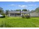 Spacious backyard with lush green grass, mature trees, and the back of the house featuring a screened in sun room at 604 Longstreet St, Summerville, SC 29486