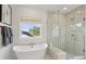 Bright bathroom featuring a modern soaking tub, glass enclosed shower, and white tile floors at 766 Maynard Ln, Summerville, SC 29486