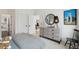 Stylish bedroom featuring a gray dresser, round mirror, comfy bed, and an adjacent room with a view into another space at 766 Maynard Ln, Summerville, SC 29486