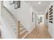 Bright hallway with hardwood floors, a staircase with white railing, and decorative artwork creating an inviting space at 766 Maynard Ln, Summerville, SC 29486