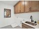 Functional laundry room features wooden cabinets, a stainless steel sink, a quirky artwork piece, and modern fixtures at 766 Maynard Ln, Summerville, SC 29486