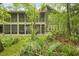 Beautiful exterior featuring a screened porch, manicured lawn, and lush tropical foliage for a relaxing outdoor space at 8400 Camp Gregg Ln, North Charleston, SC 29418
