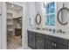 Bathroom with double sink, gray cabinets, marble countertop, rope mirrors, and door to closet at 16 Oakwood Ln, Edisto Island, SC 29438