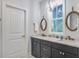 Bathroom with double sink, white marble countertop, gray cabinets, elegant mirrors, and natural light at 16 Oakwood Ln, Edisto Island, SC 29438