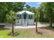 Charming coastal home featuring a light blue exterior, white trim, elevated design, and lush landscaping with palm trees at 16 Oakwood Ln, Edisto Island, SC 29438