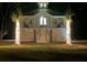 Night view of a charming elevated coastal home with lighted palm trees and an inviting warm glow from within at 16 Oakwood Ln, Edisto Island, SC 29438