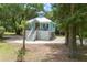 Inviting exterior showcasing a charming light blue coastal home with a white roof, and a spacious yard with mature trees at 16 Oakwood Ln, Edisto Island, SC 29438