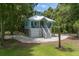 Picturesque exterior featuring a light blue coastal home with an elevated design, complemented by lush landscaping and gravel driveway at 16 Oakwood Ln, Edisto Island, SC 29438