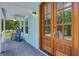 Beautiful wooden front door with glass panes with rocking chairs on the front porch and a ceiling fan at 16 Oakwood Ln, Edisto Island, SC 29438