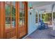 Charming front porch with a beautiful wooden door, inviting rocking chair, and a ceiling fan, perfect for relaxing at 16 Oakwood Ln, Edisto Island, SC 29438