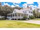 Spacious home with a wide covered porch, ceiling fans, manicured lawn, and a charming architectural style at 165 Village Ponds Dr, Summerville, SC 29483
