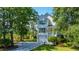 Inviting two-story home with a manicured lawn, white siding, and a charming front porch amidst lush trees at 1971 N North Creek Dr, Mount Pleasant, SC 29466