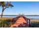 Tranquil view of a wooden dock extending into the calm water, framed by natural greenery and a clear blue sky at 1971 N North Creek Dr, Mount Pleasant, SC 29466