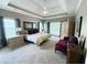 Spacious main bedroom with a tray ceiling, carpet flooring, natural light, and a cozy sitting area at 213 Ashmont Dr, Wando, SC 29492