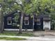 Modest single-story home featuring a black exterior, brick foundation, awning accents and mature trees at 2334 Kent Ave, North Charleston, SC 29405