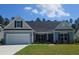 Charming one-story home with blue siding, a two-car garage, and a well-manicured front lawn at 265 Huguenot Trl, Huger, SC 29450