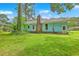 A backyard shows a home with a brick chimney, lush green grass, and mature trees at 312 Woodward Blvd, Summerville, SC 29483