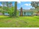 The home's backyard includes a brick chimney, an abundance of grass, and shaded by lush trees at 312 Woodward Blvd, Summerville, SC 29483