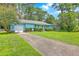A cute, light blue house with attached garage surrounded by grass, trees, and a long concrete driveway at 312 Woodward Blvd, Summerville, SC 29483