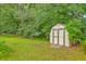A backyard contains a wooden shed surrounded by green grass and mature trees at 312 Woodward Blvd, Summerville, SC 29483