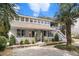 Charming two-story home featuring a welcoming front porch, lush landscaping, and a side staircase to a deck at 504 W Ashley Ave, Folly Beach, SC 29439