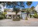 Charming two-story home featuring a welcoming front porch, lush landscaping, and a side staircase to a deck at 504 W Ashley Ave, Folly Beach, SC 29439