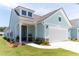 Charming light blue house with a two car garage, black door and well manicured yard at 754 Blue Iris Way, Summerville, SC 29486