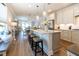 Bright, open kitchen with stainless appliances, seating at island, wood floors, and open view of living area at 754 Blue Iris Way, Summerville, SC 29486