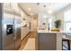 Well-lit kitchen equipped with stainless steel appliances, white cabinets, island with seating and wood floors at 754 Blue Iris Way, Summerville, SC 29486
