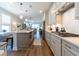 Open-concept kitchen showcasing stainless steel appliances, white cabinets, island with seating and wood floors at 754 Blue Iris Way, Summerville, SC 29486