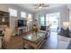 Bright living room with wood floors, a ceiling fan, and access to the screened patio via sliding glass doors at 754 Blue Iris Way, Summerville, SC 29486