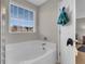 Clean white bathtub located next to a window for natural light and a white paneled door with towel hooks at 9009 Cat Tail Pond Rd, Summerville, SC 29485