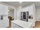 Stylish kitchen boasts white cabinets, quartz countertops, stainless steel refrigerator, and seamless flow into other living areas at 9009 Cat Tail Pond Rd, Summerville, SC 29485