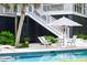 The backyard pool has an umbrella, lounge chairs, and an elevated house with stairs at 932 Middle St, Sullivans Island, SC 29482