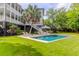 View of a backyard pool surrounded by green grass, with chairs and a two-story home in the background at 932 Middle St, Sullivans Island, SC 29482