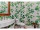 This half bath features leaf-patterned wallpaper, a woven mirror frame, and a pedestal sink at 932 Middle St, Sullivans Island, SC 29482