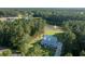 Aerial view of a light blue two-story home surrounded by lush, green trees and tranquil pond at 1130 Plantation Overlook Dr, Moncks Corner, SC 29461