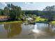 Aerial view of a tranquil pond with fountain feature and nearby dock surrounded by lush trees at 1130 Plantation Overlook Dr, Moncks Corner, SC 29461
